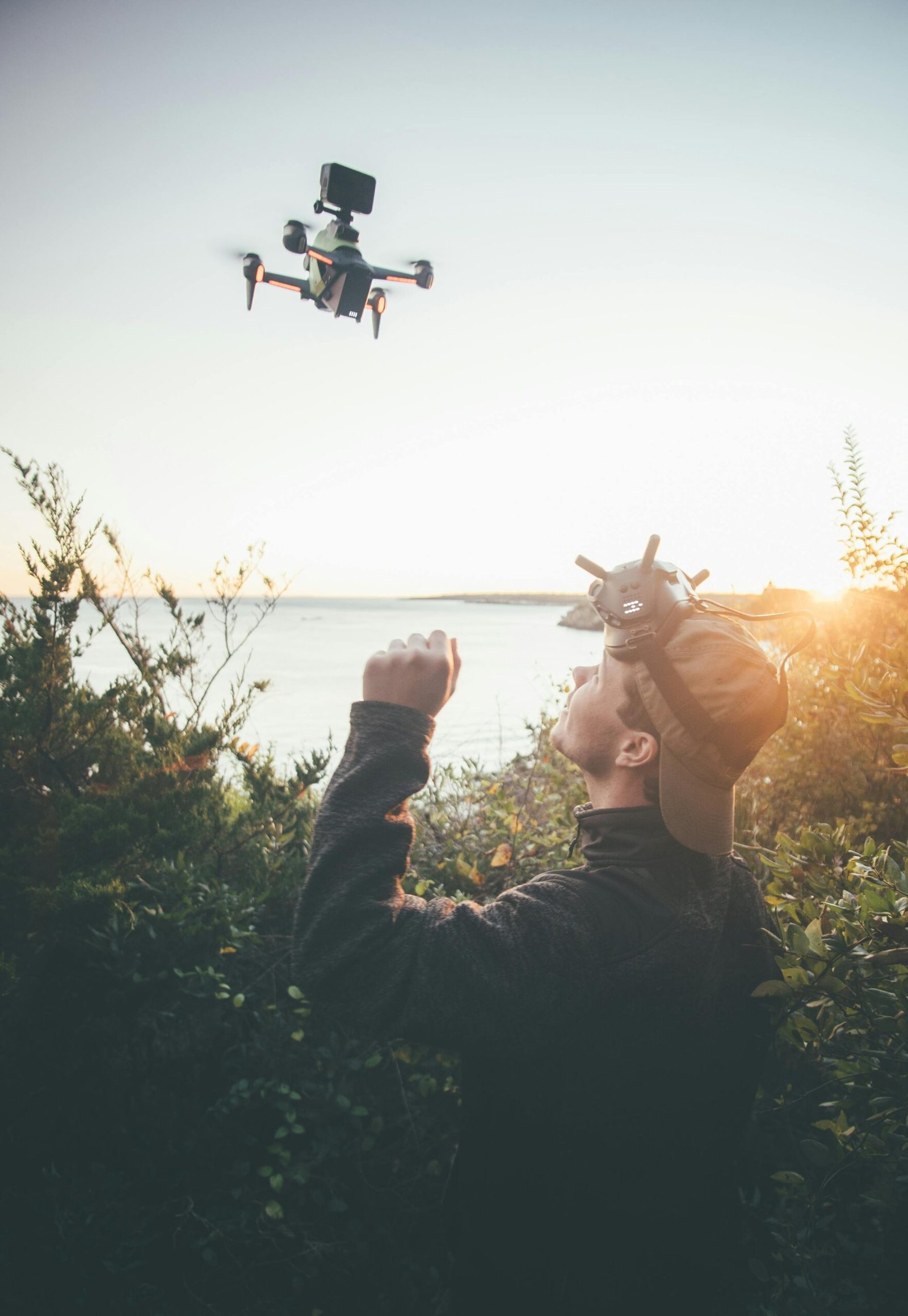 A man operates a drone at sunset, capturing stunning outdoor landscapes with high-tech gear.